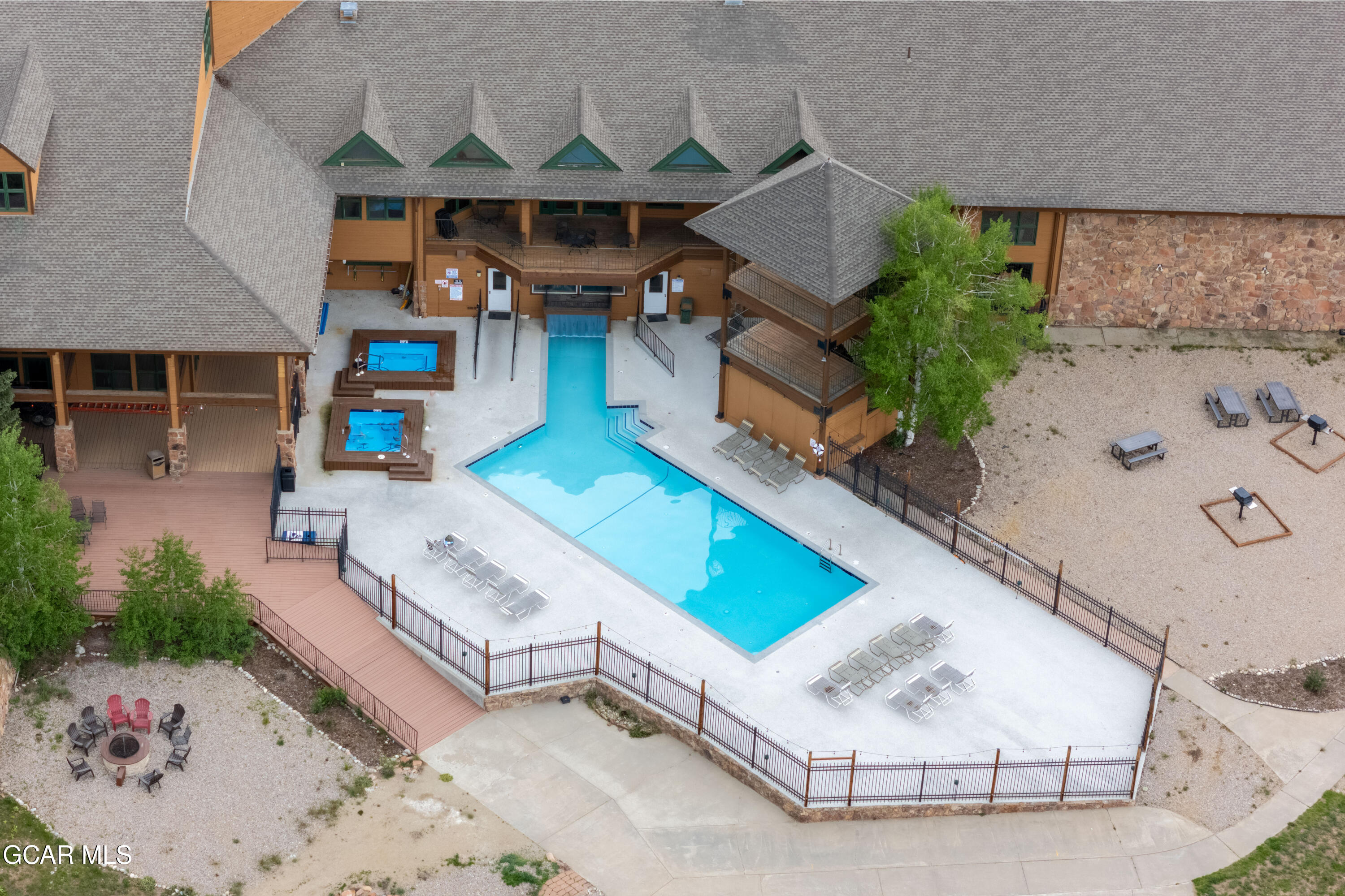 Aerial view of a courtyard pool and two spas surrounded by lodge-style buildings and lounge areas.