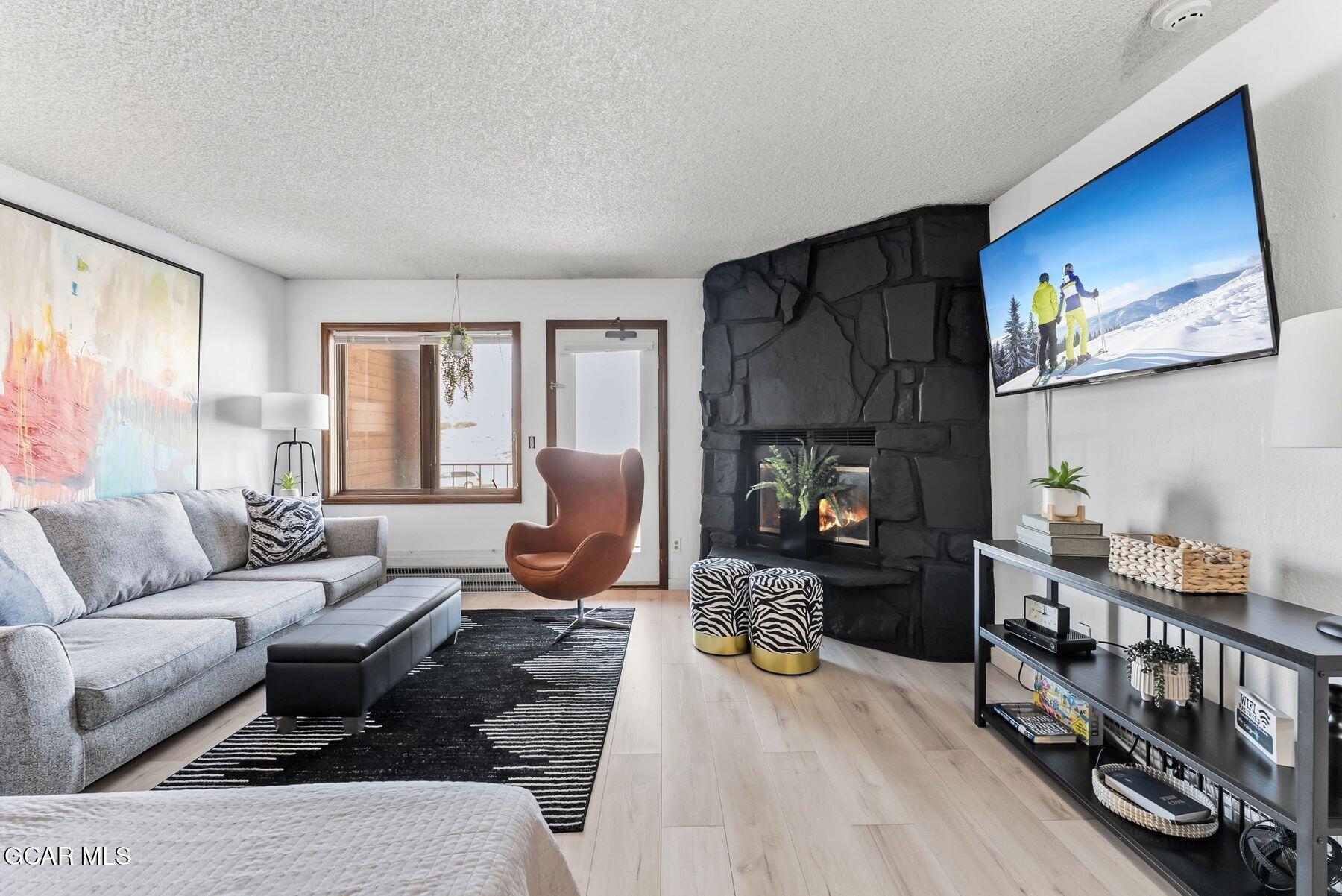Living room with a black stone fireplace, gray sectional, and wall-mounted television.