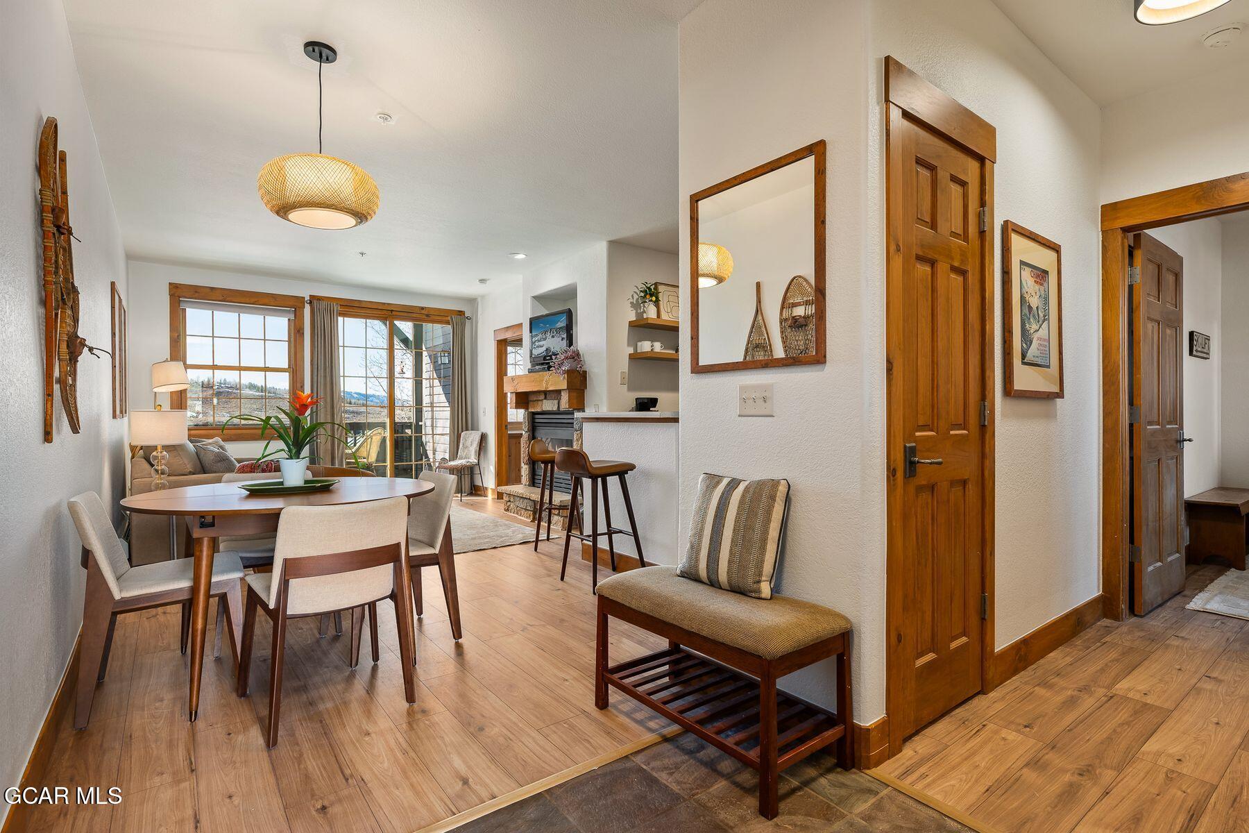 Dining and living area with a fireplace, wood-trimmed windows, and snowy mountain views.