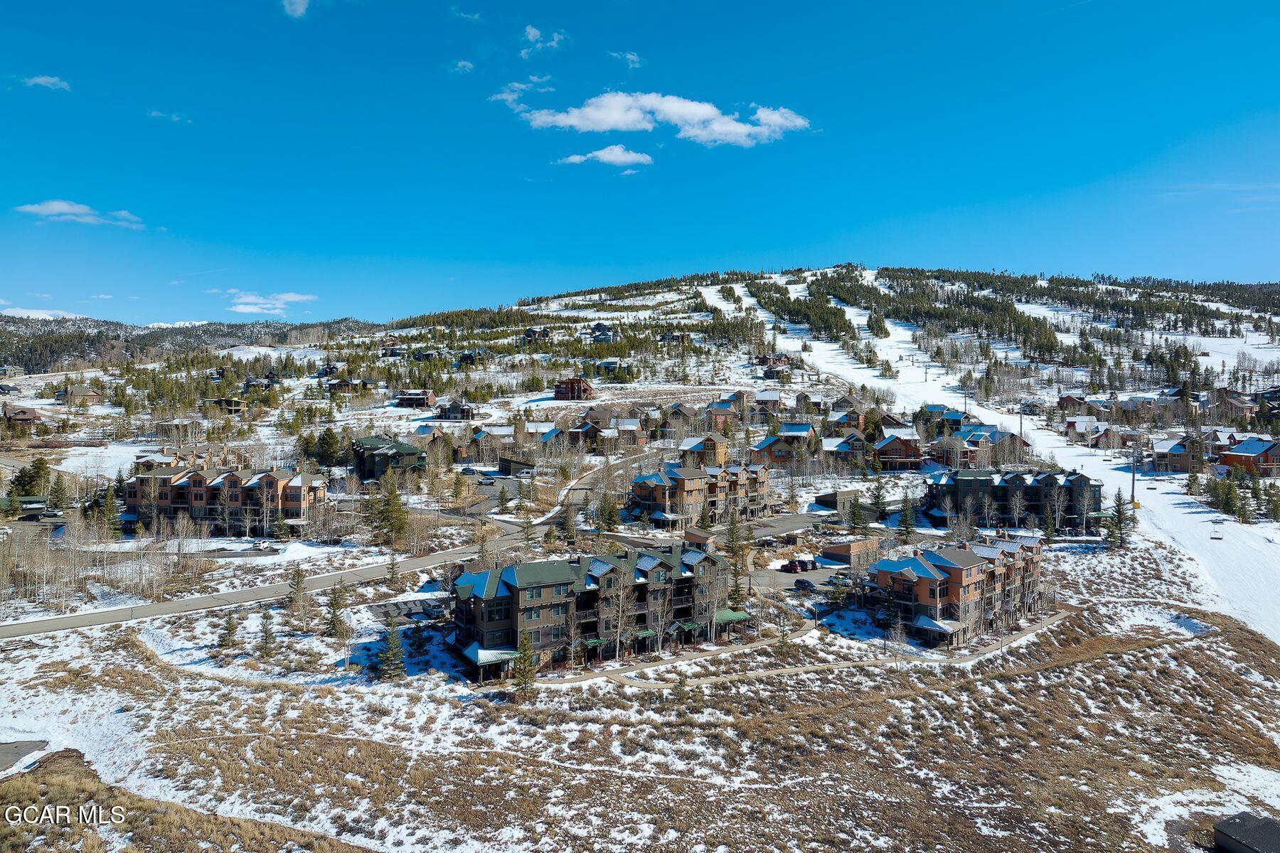 Aerial view of snow-covered homes and ski runs on a mountain hillside.