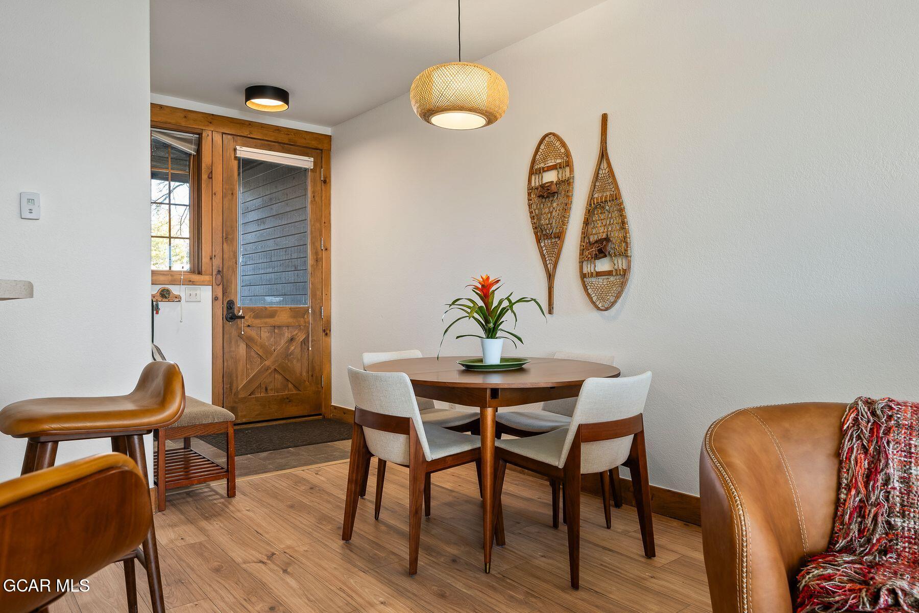 Dining area with a round wooden table, rustic glass door, and snowshoes displayed on the wall.