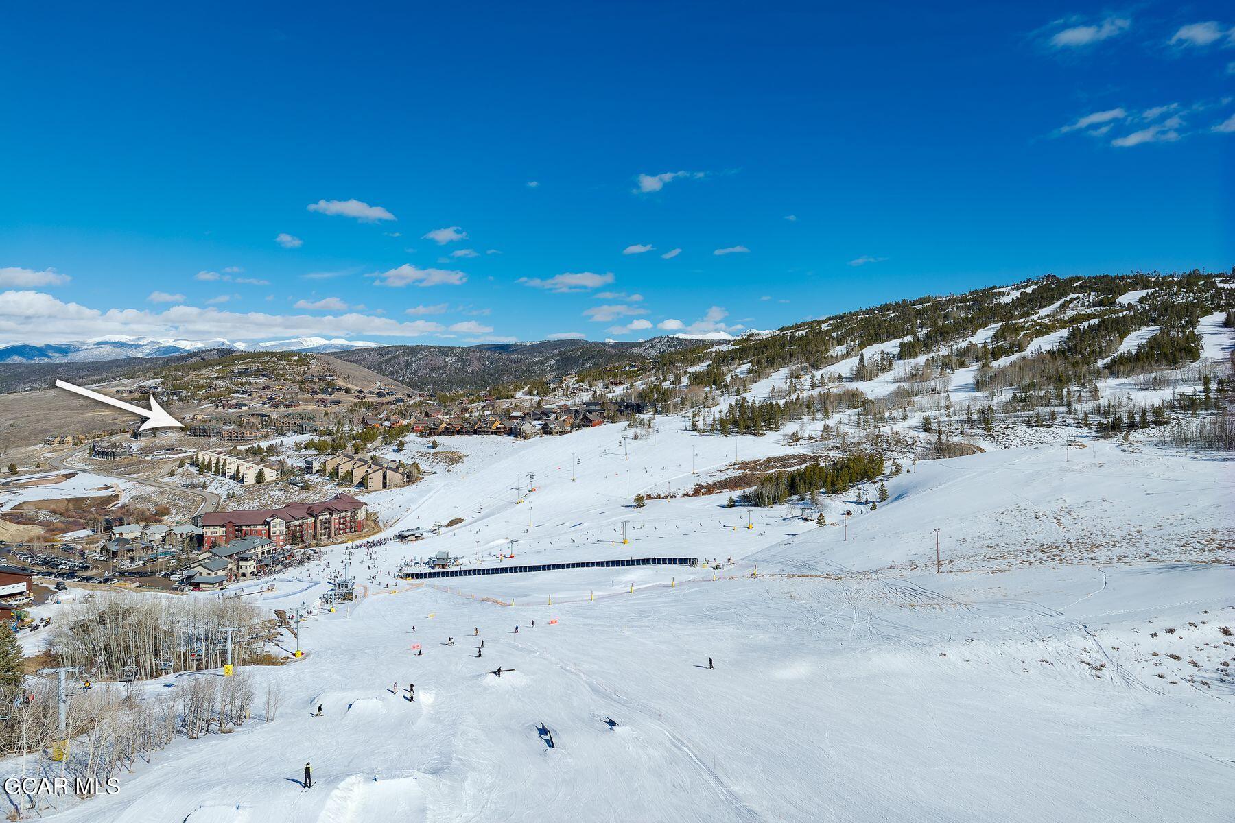 Snowy ski resort and mountain community, with an arrow pointing toward a building.
