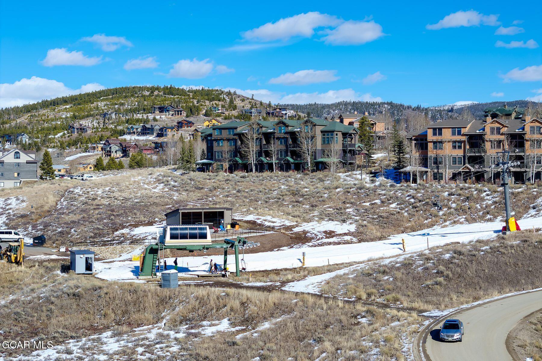 Mountain condos and a ski lift on a partly snow-covered slope.
