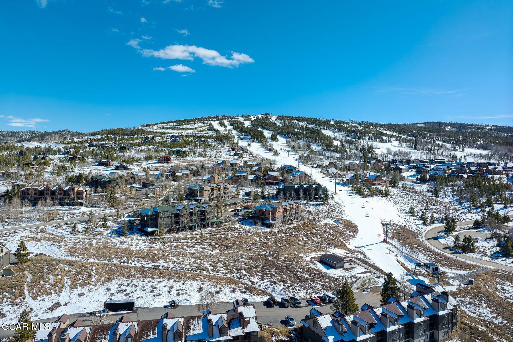Aerial view of a snowy ski area and neighborhood with mountain runs and homes.