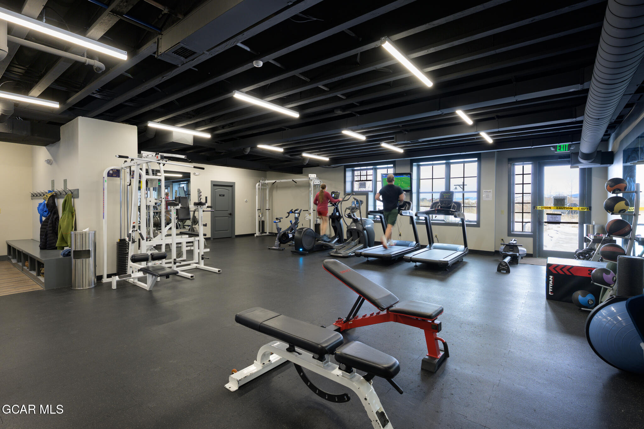 Fitness center with treadmills by large windows and weight equipment throughout.