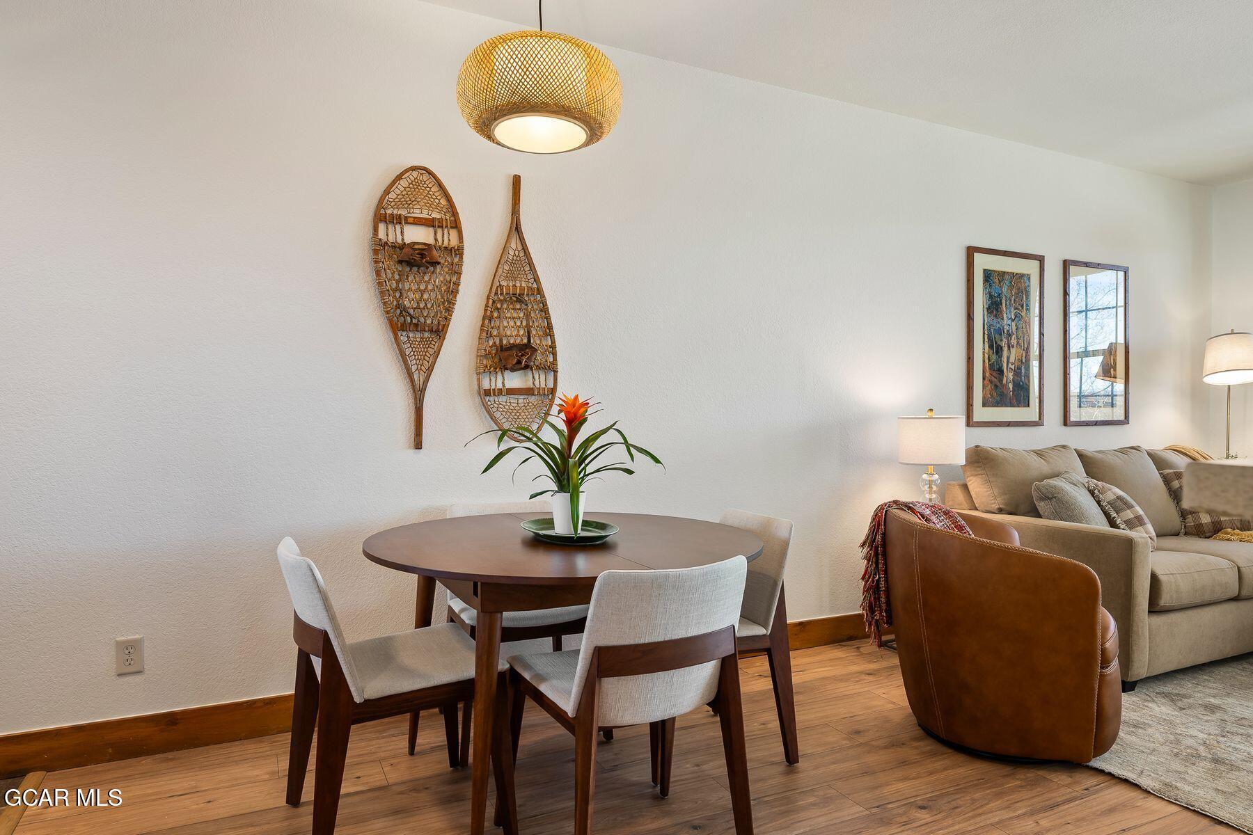 Dining and living area with a round table, woven snowshoe decor, and beige seating.