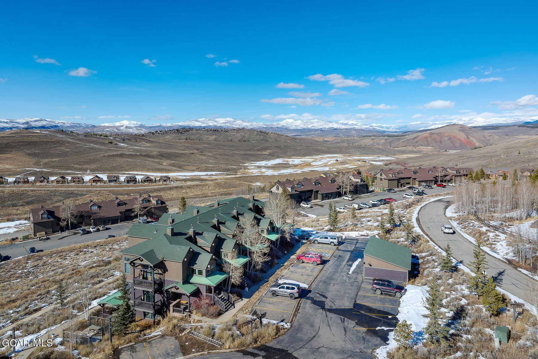 Aerial view of homes in a mountain community with snow-covered peaks in the distance.