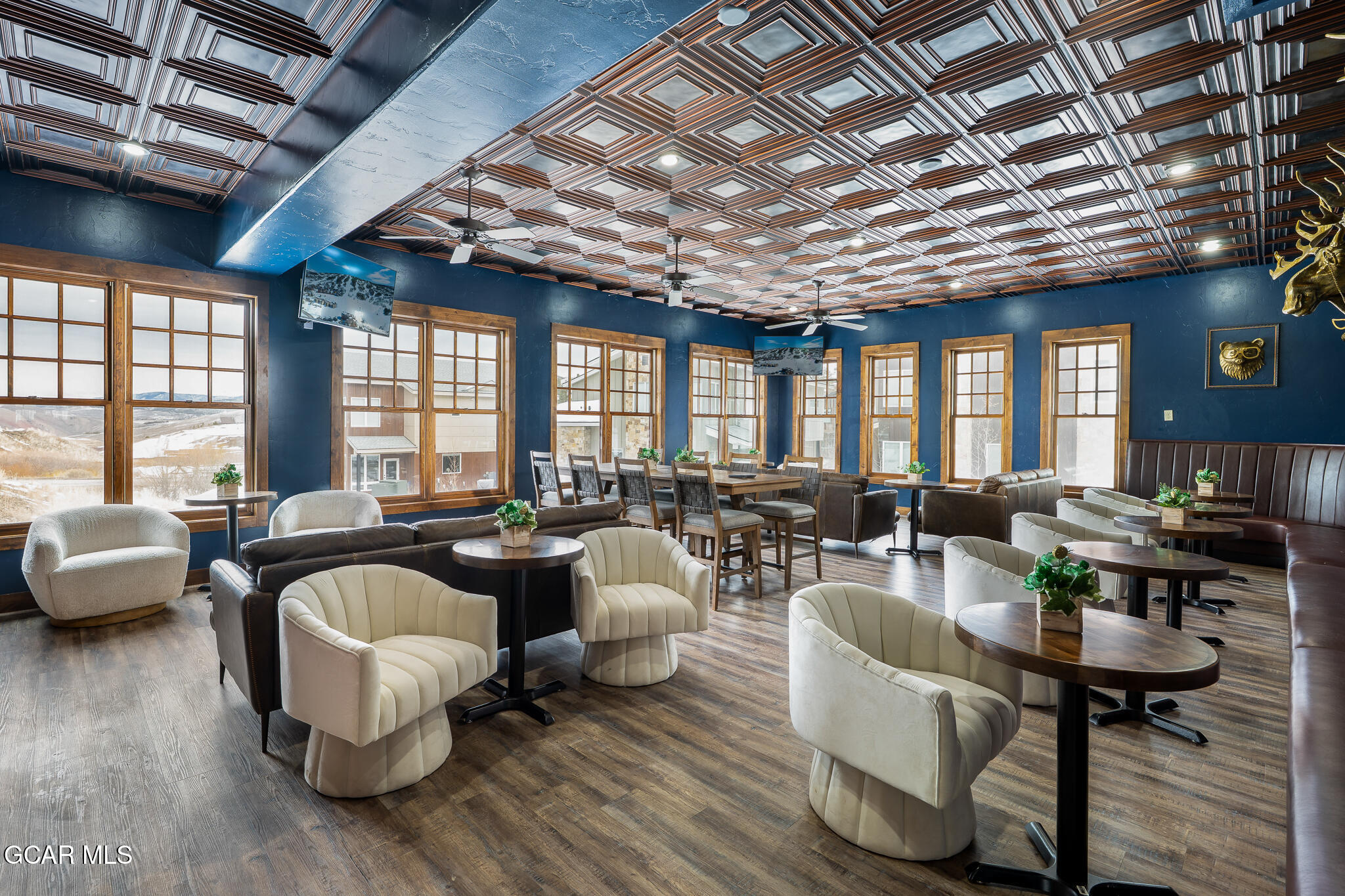 Furnished lounge and dining area with a geometric ceiling and large windows overlooking snowy scenery.