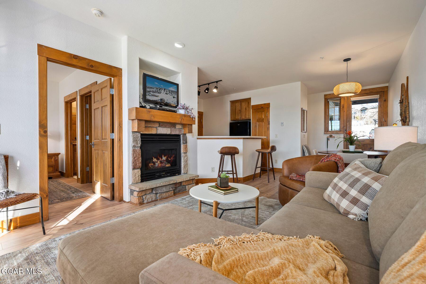 Living room with a stone fireplace, sectional sofa, and open kitchen bar.