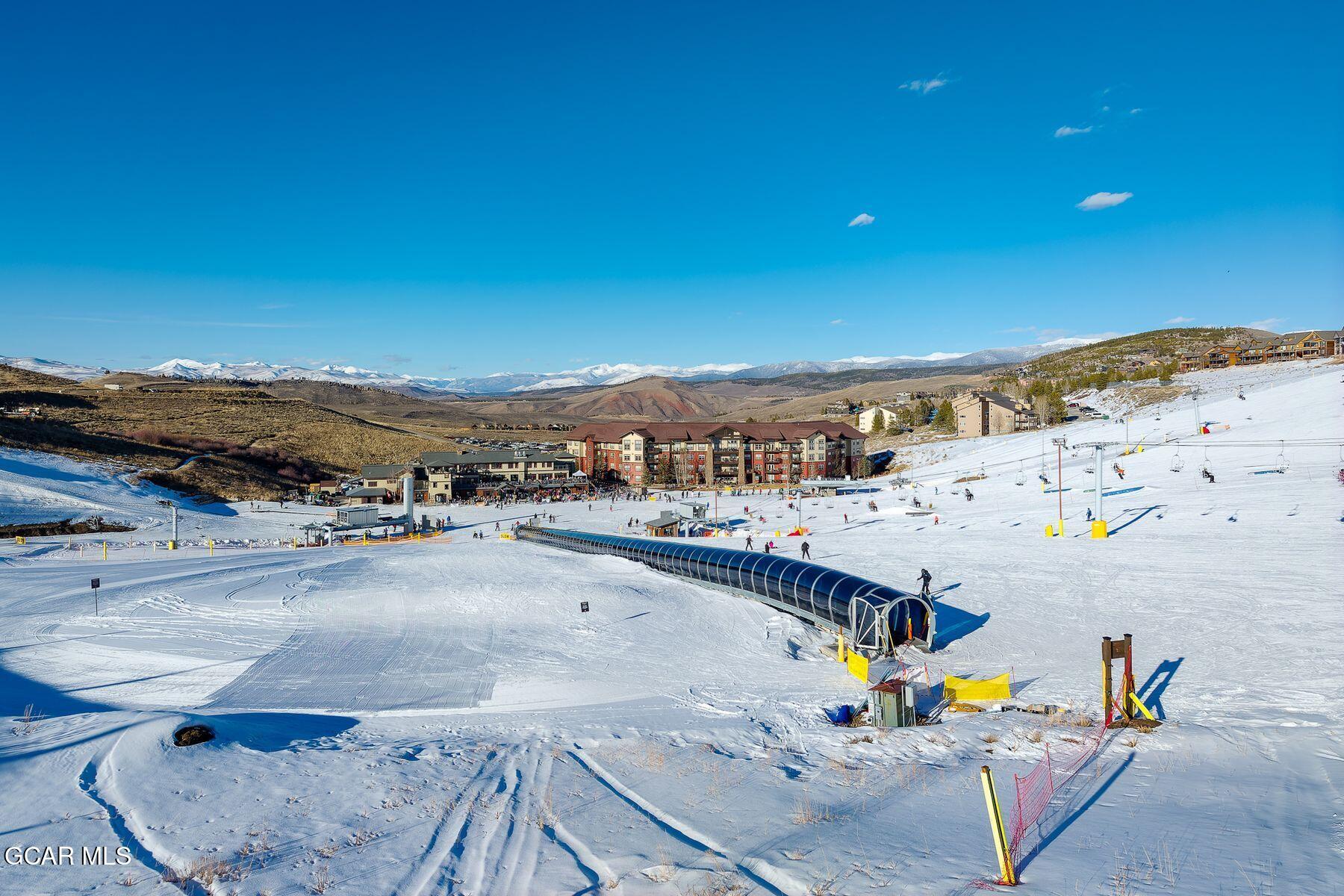 Snowy ski area with resort buildings, ski lifts, and mountain views.