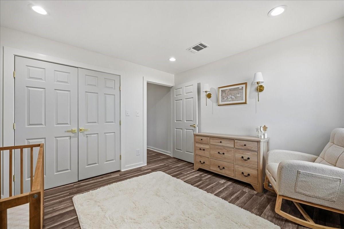 Furnished room with paneled closet doors, a wood dresser, and an upholstered chair.