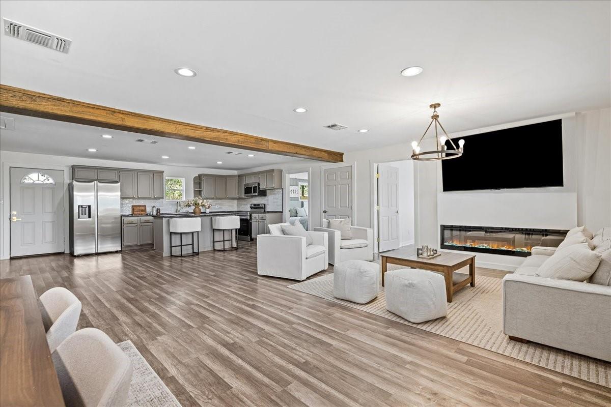 Open-plan living room and kitchen with white seating, gray cabinets, and a linear fireplace.