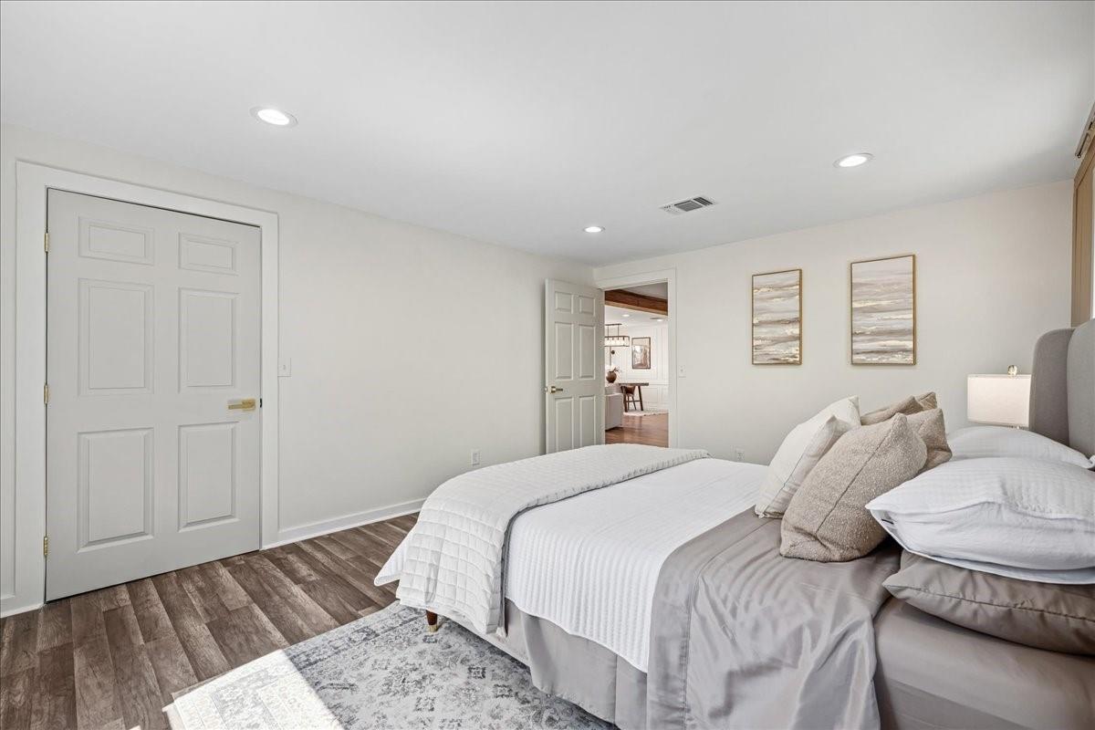 Bedroom with a large white-and-gray bed, patterned rug, and wood-look flooring.