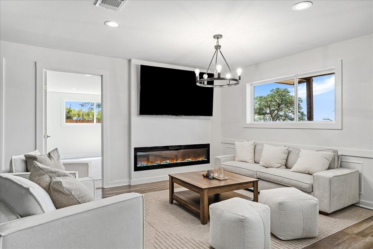 Living room with white sofas, a wood coffee table, and a wall-mounted TV above an electric fireplace.