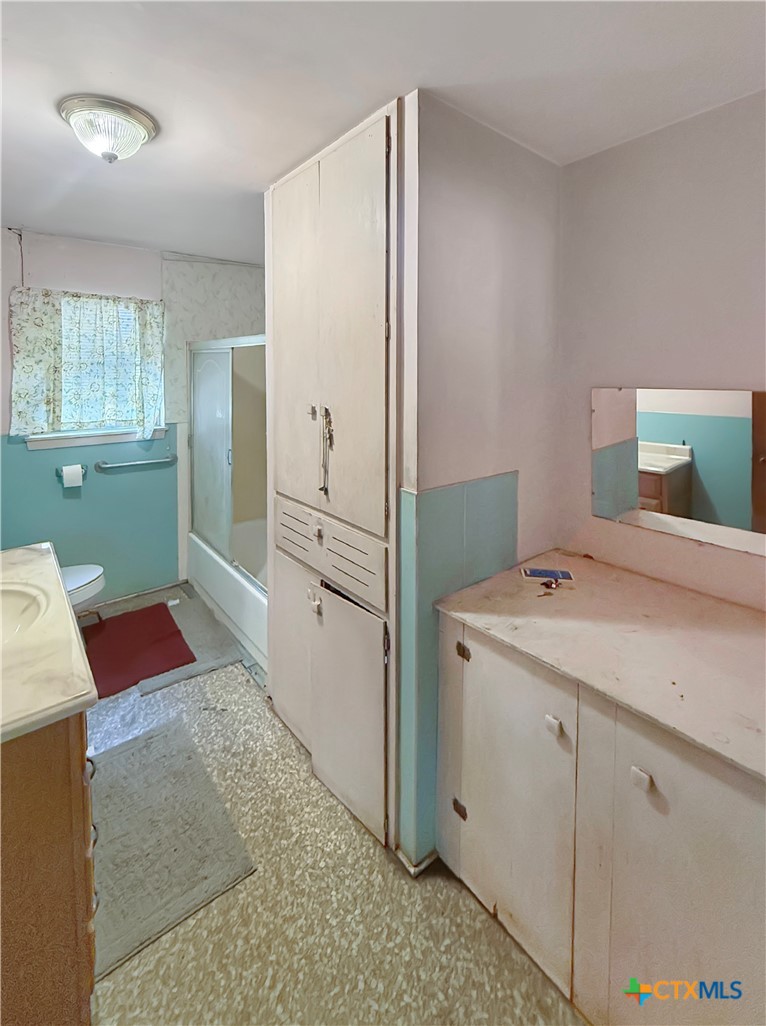 Bathroom with a tall built-in cabinet separating the bathtub and shower from the vanity.