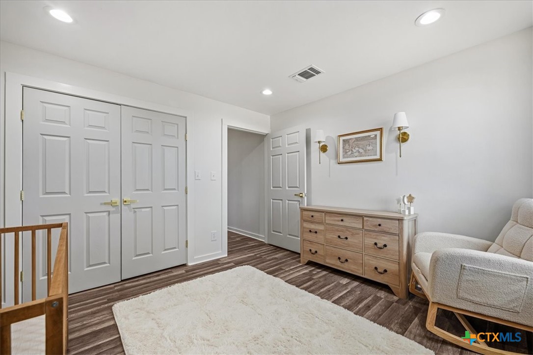Bedroom with double closet doors, a wooden dresser, and an upholstered rocking chair.