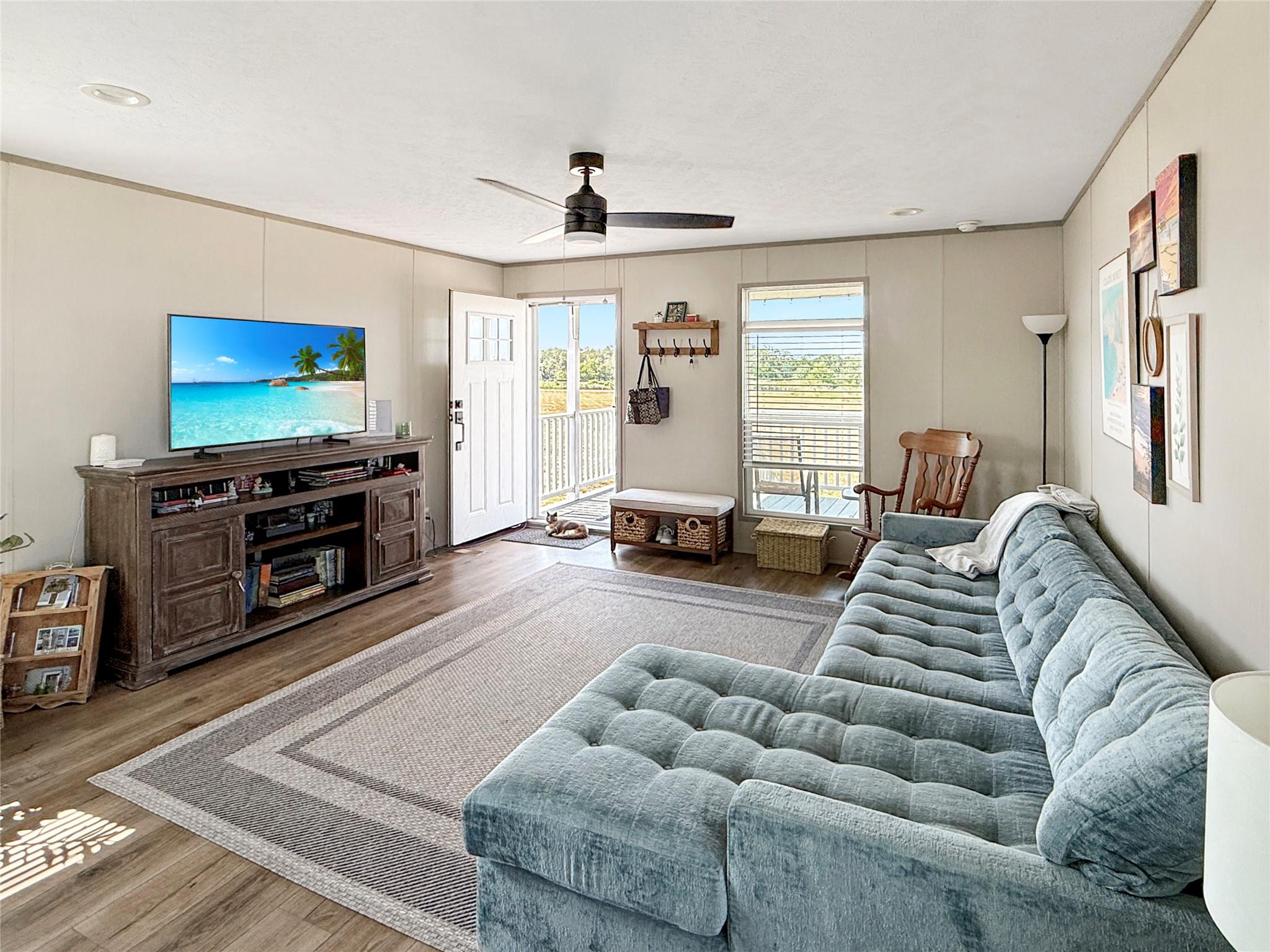 Living room with a blue-gray sectional, patterned rug, and open door to a porch.