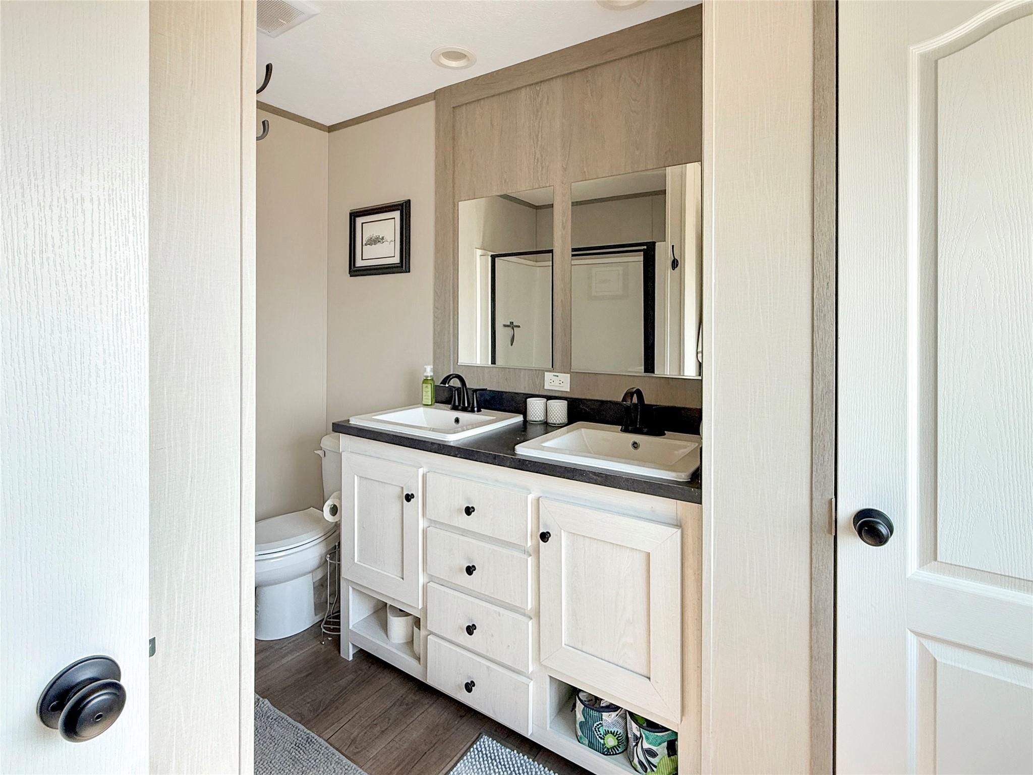 Bathroom with a white double-sink vanity, dark countertop, and large mirrors.