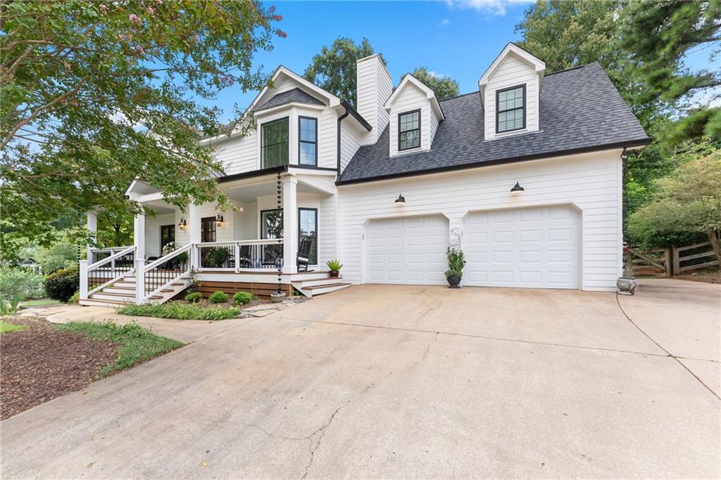White two-story home with dormer windows, a covered porch, and an attached two-car garage.
