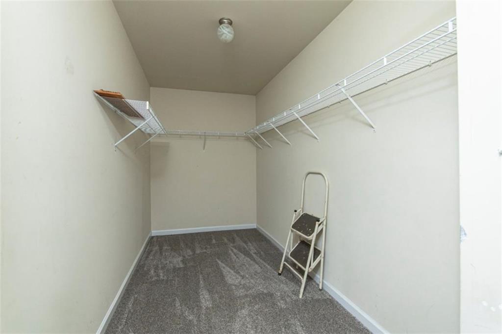 Walk-in closet with wire shelving on three walls, gray carpet, and a step stool.