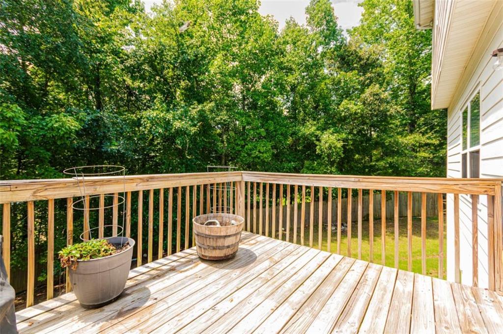 Wooden backyard deck with planters overlooking a lush wooded yard.