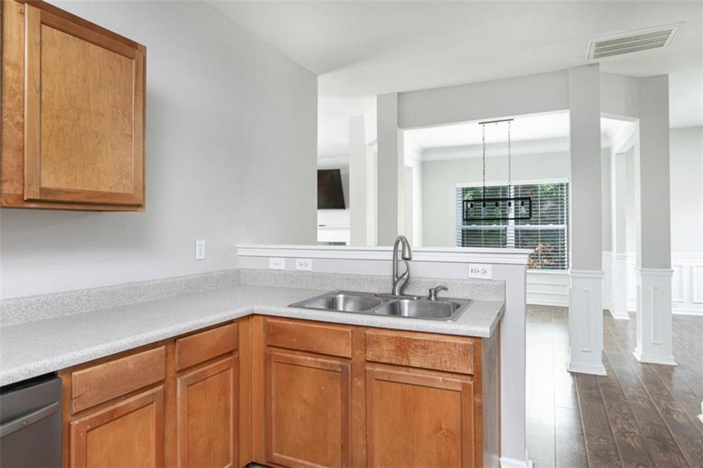 Kitchen with warm wood cabinets and a sink overlooking an open room with dark wood floors.