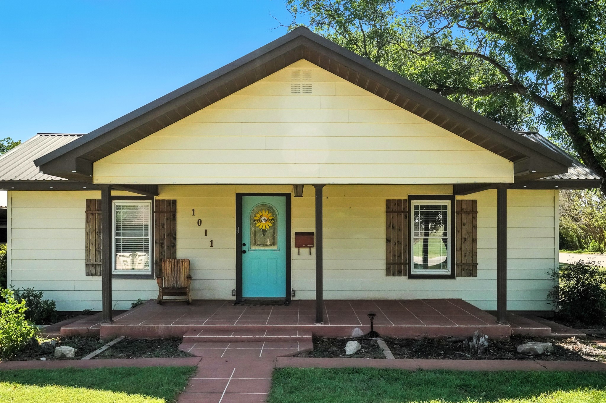 Home at 1011 Trundy with a turquoise front door and covered tiled porch.