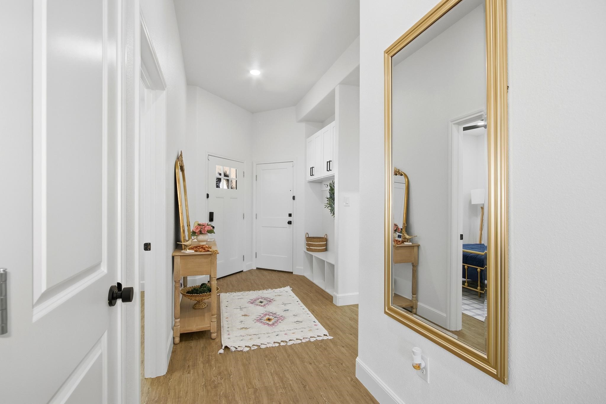 Bright entryway with a gold-framed mirror, built-in cabinets, and floral runner rug.