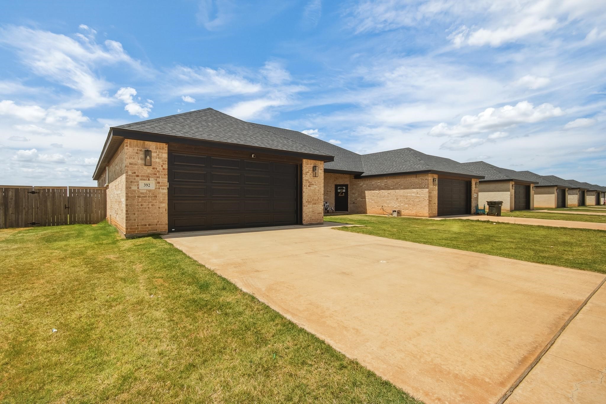 Brick home at 392 Kristi Path with a dark double garage door and broad concrete driveway.