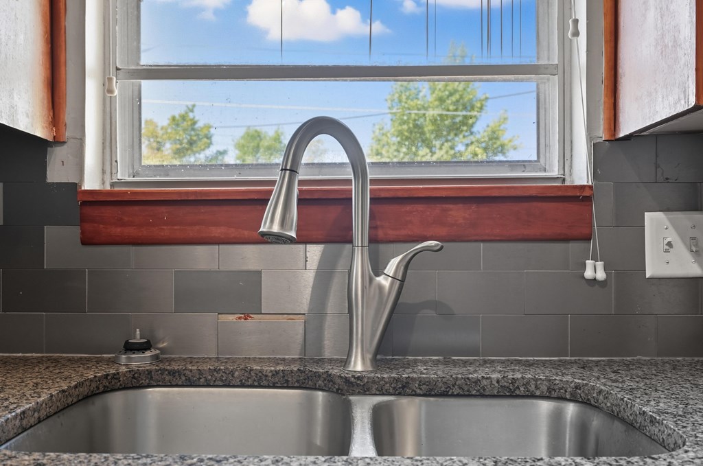 Double-basin kitchen sink with a curved faucet beneath a window.