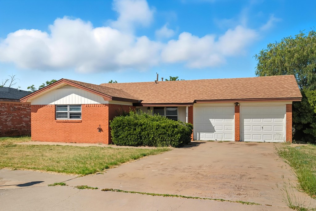 Single-story red-brick house with a two-car garage and wide concrete driveway.