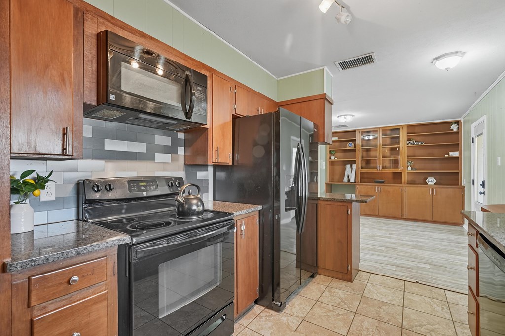 Kitchen with wood cabinets, black appliances, tiled floors, and built-in shelving.