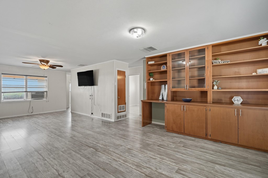 Living room with gray flooring and a large built-in wooden shelving unit.