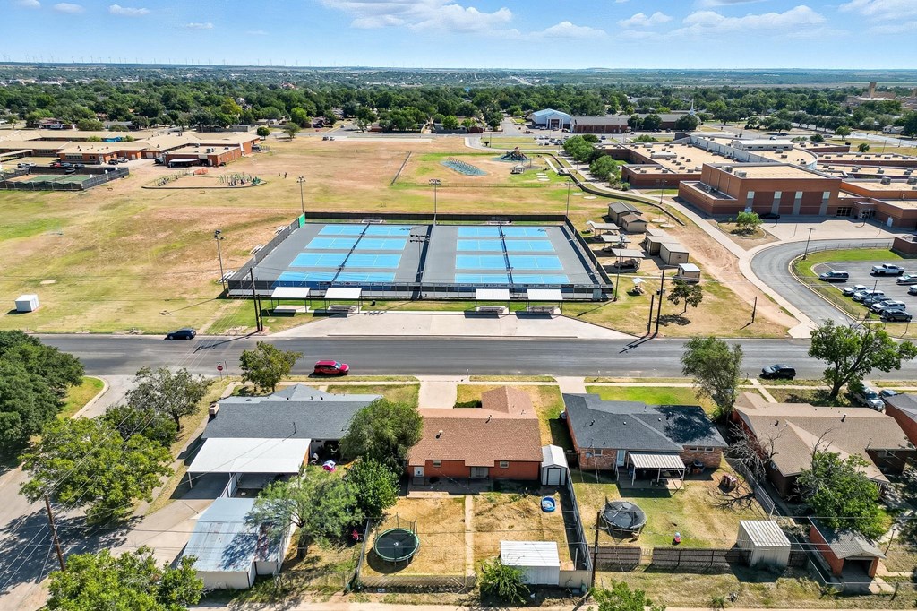 Aerial neighborhood view with homes in the foreground and blue tennis courts across the street.