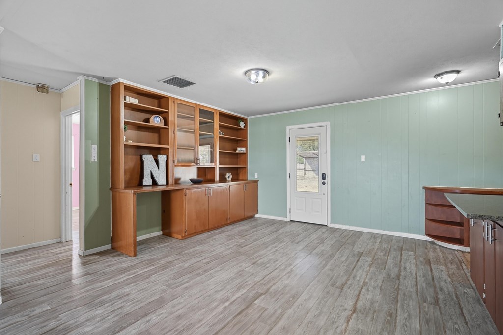 Empty room with built-in wooden cabinetry, pale green paneled walls, and gray plank flooring.