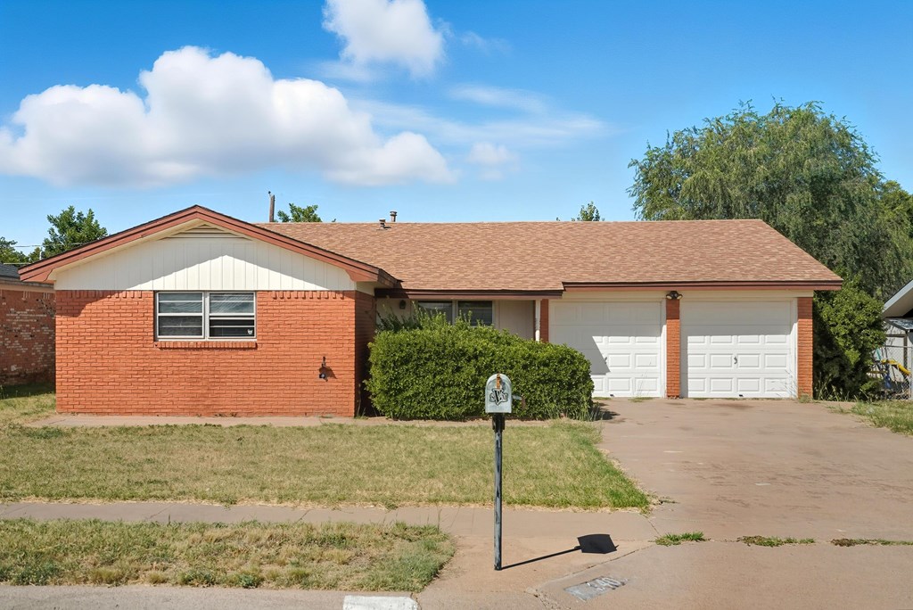 Single-story brick home with two garage doors, a driveway, and a dry front lawn.