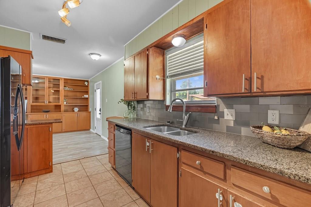 Kitchen with warm wood cabinetry, a double-basin sink beneath the window, and built-in shelves.