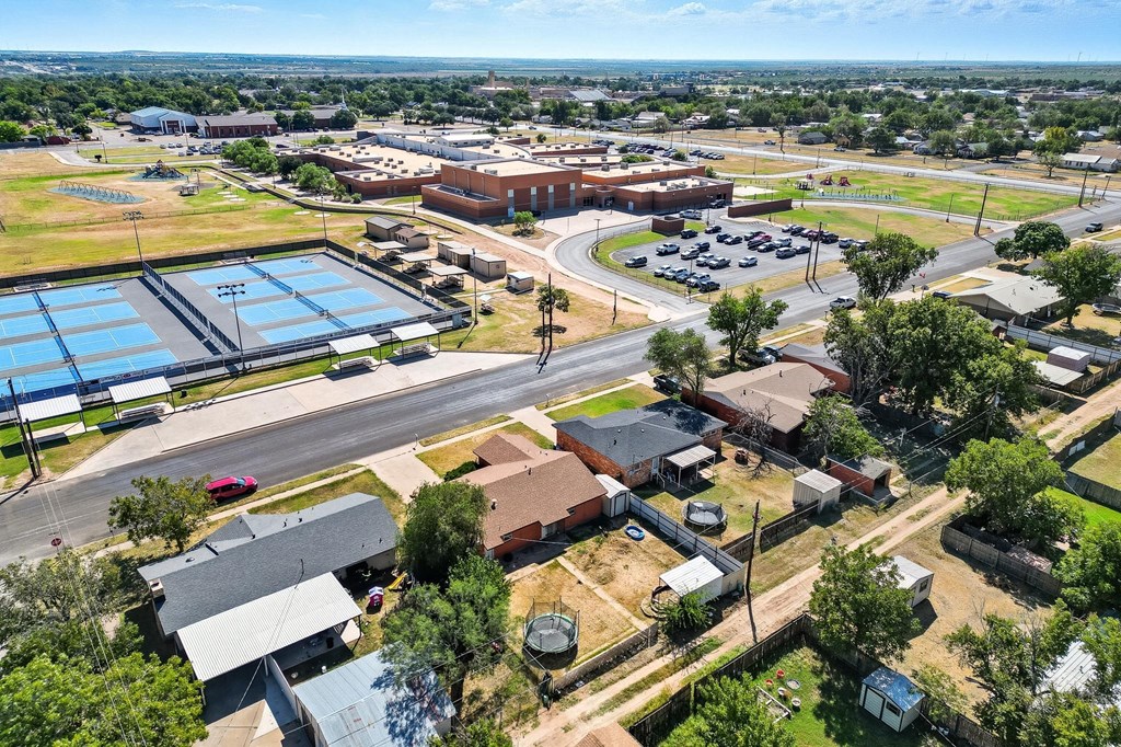 Aerial view of a home near tennis courts and a large school complex.