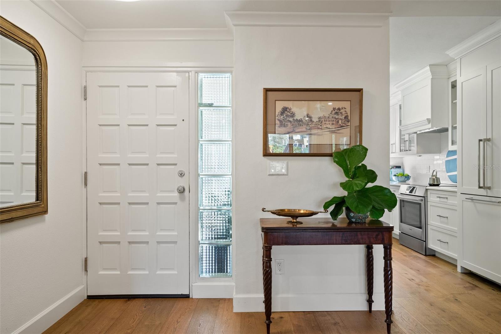 Condo entryway with glass-block windows, a dark wood console table, and the kitchen beyond.