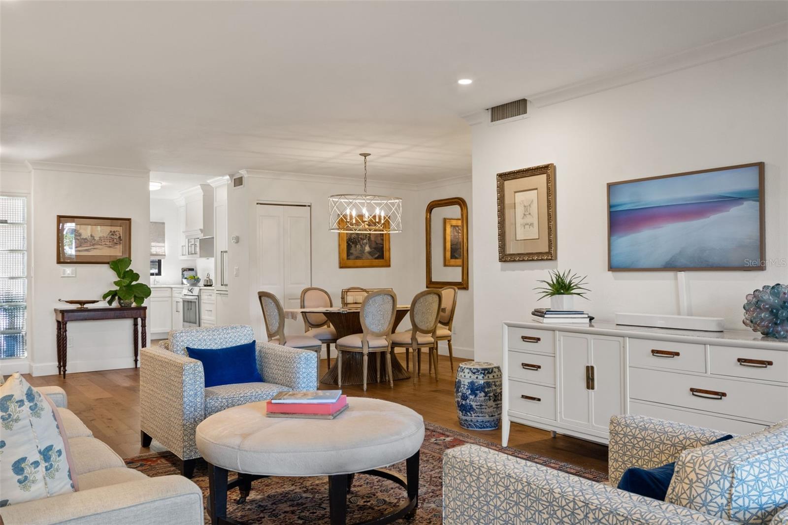 Open-plan living and dining room with patterned seating, hardwood floors, and a view into the kitchen.
