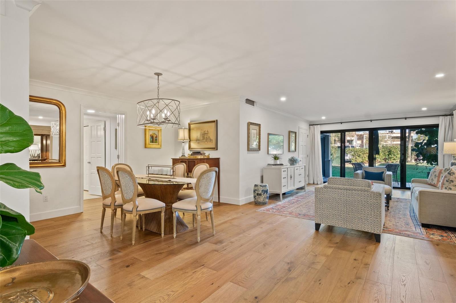 Open-plan dining and living room with hardwood floors and sliding glass doors to a garden patio.