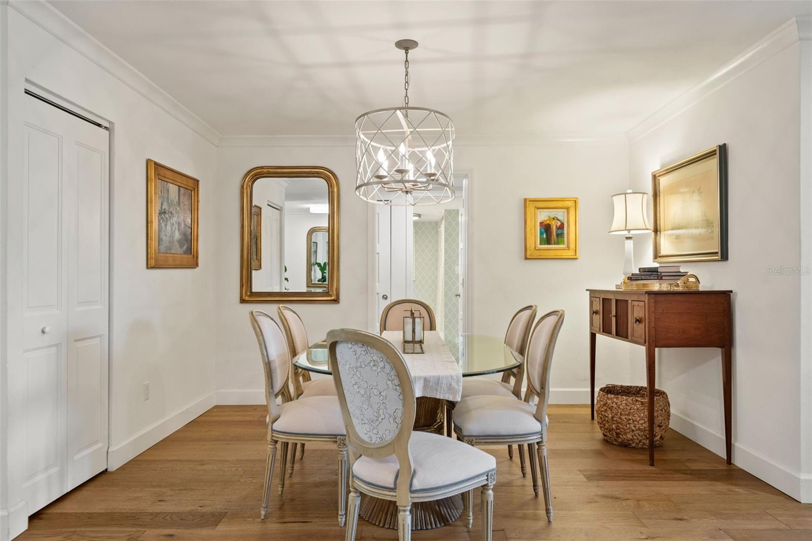 Furnished dining room with a glass-top table, upholstered chairs, and a geometric pendant chandelier.