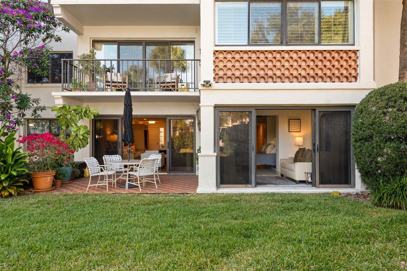 Condominium exterior with a ground-floor patio, sliding glass doors, and an upper-level balcony.