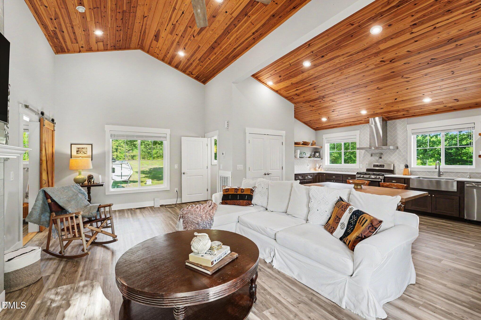 Open-plan living room and kitchen with a vaulted wood ceiling and white sectional sofa.