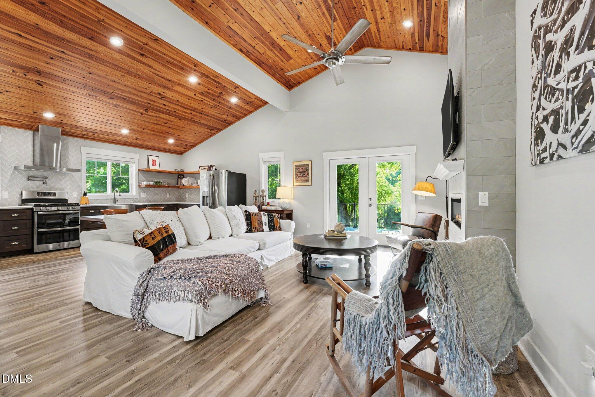 Open-plan living room and kitchen with a vaulted cedar ceiling and white sectional sofa.