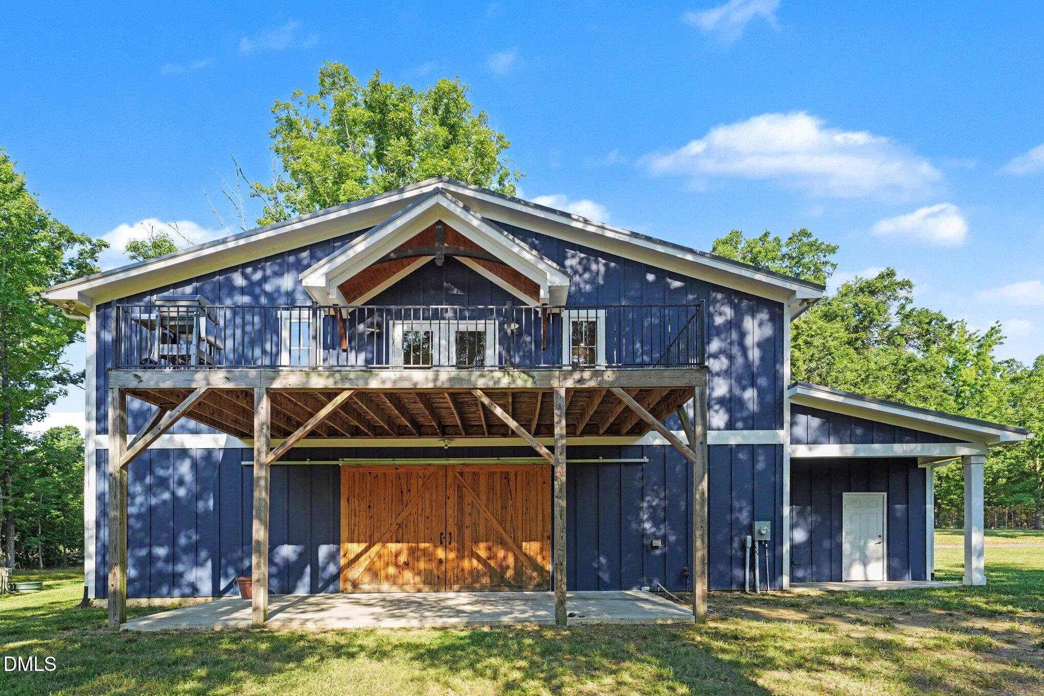 Blue home with an elevated deck, exposed timber supports, and wooden double doors.