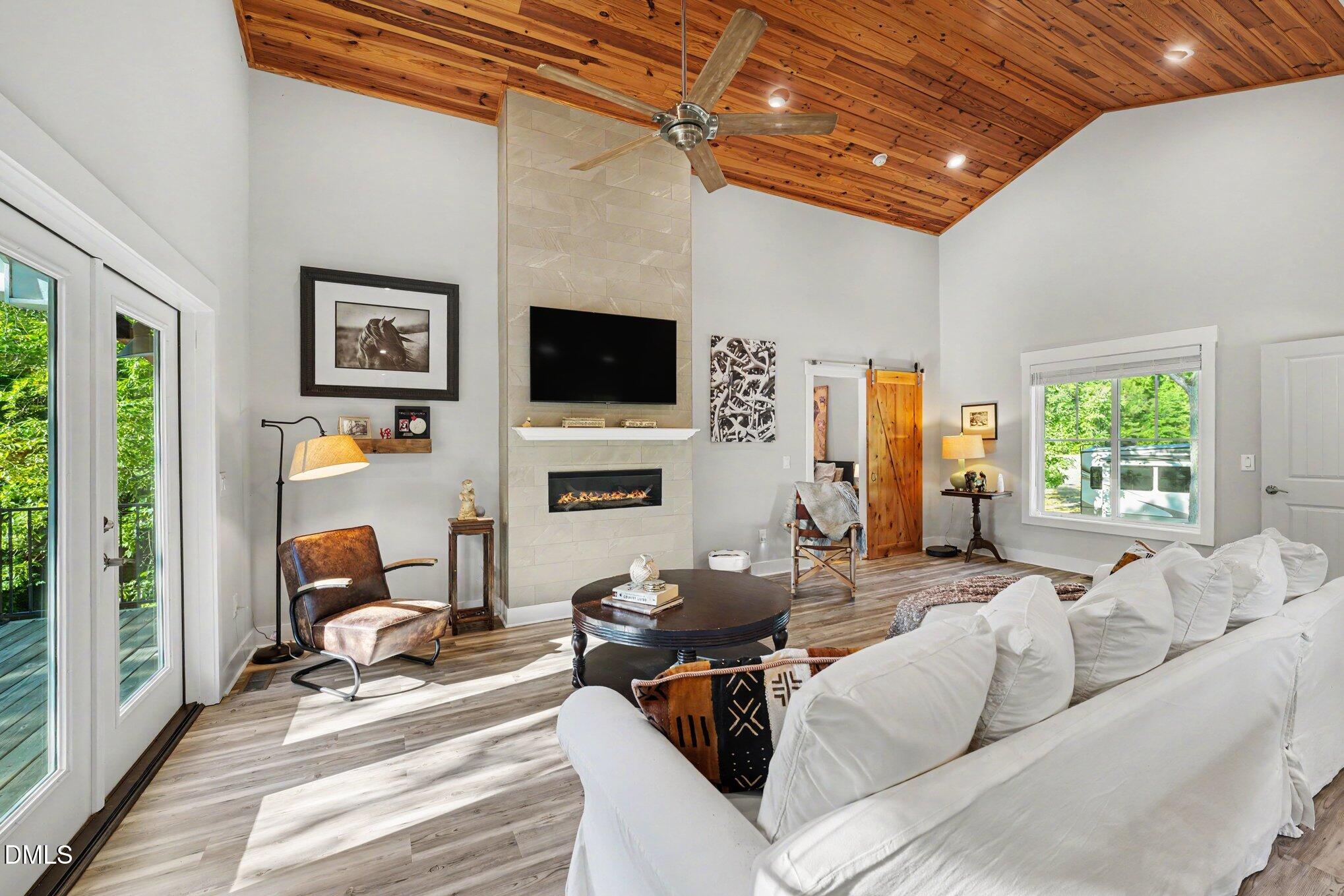 Living room with vaulted wood ceiling, tiled fireplace wall, and white sectional sofa.