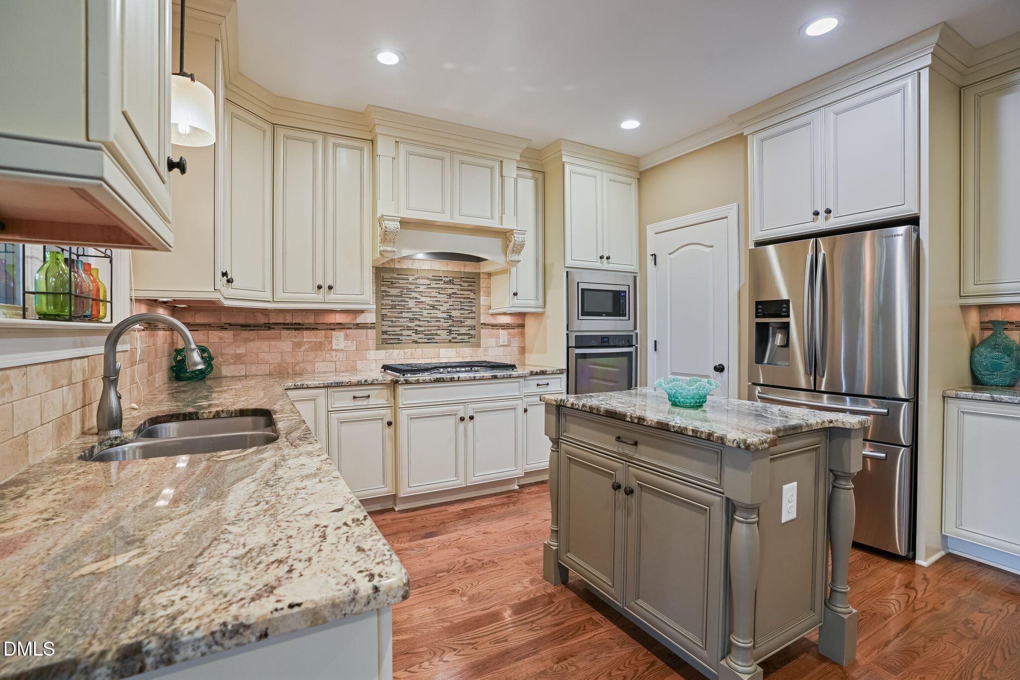 Kitchen with cream cabinets, granite counters, a central island, and stainless steel appliances.