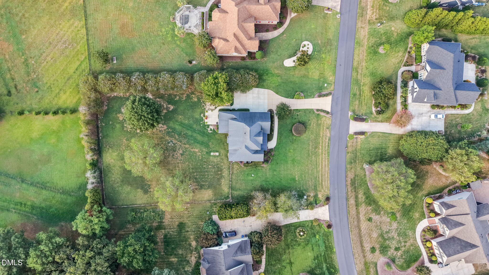 Aerial view of a gray-roofed home on a large lot beside a residential street.