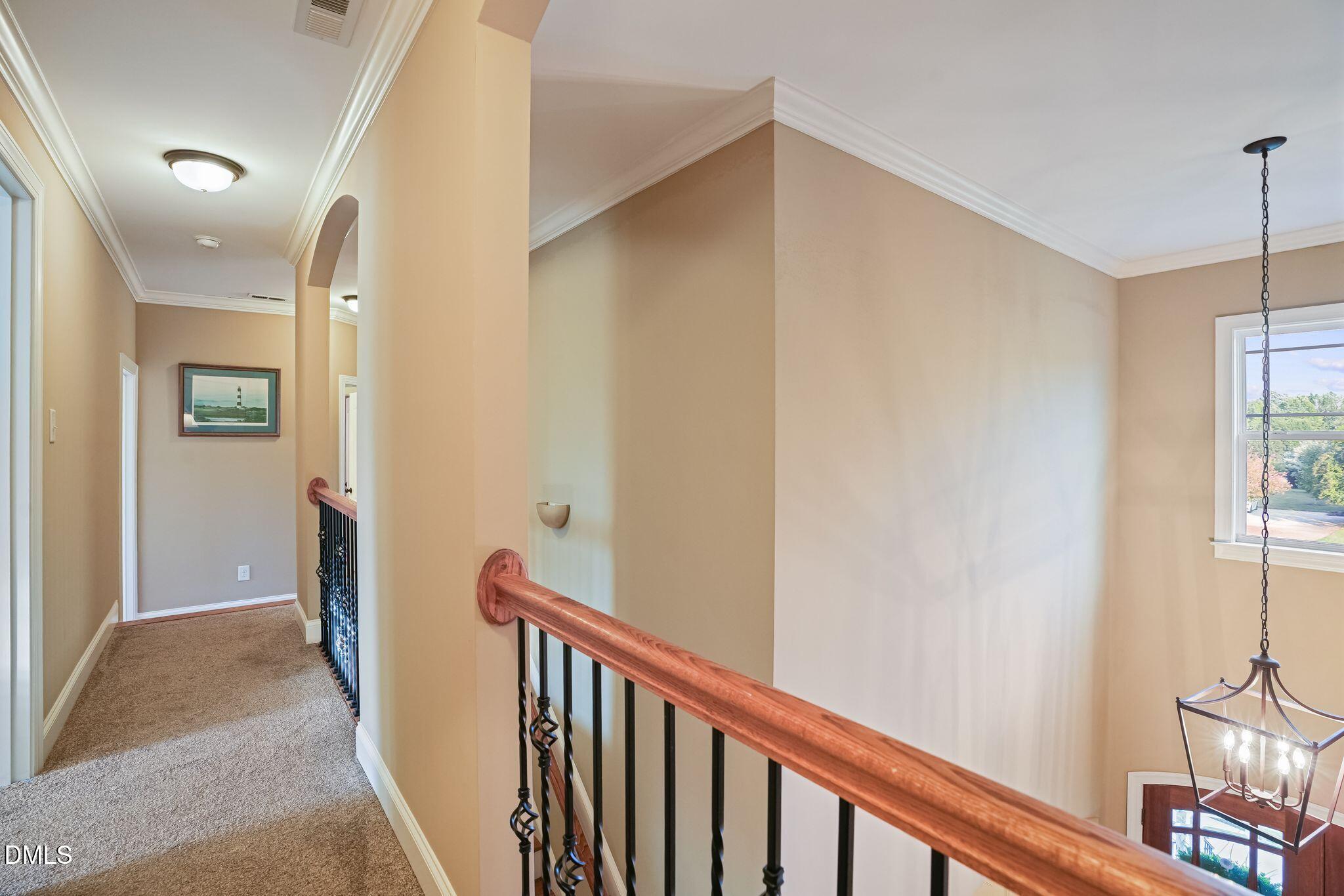 Upstairs landing overlooks a foyer, with a wood handrail and black iron balusters.